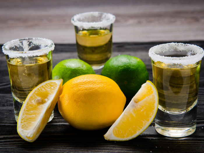 Tequila in shot glasses with salted rims, with limes and lemons on the side