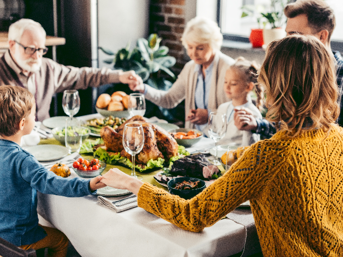 Happy beautiful family praying before holiday dinner on thanksgiving