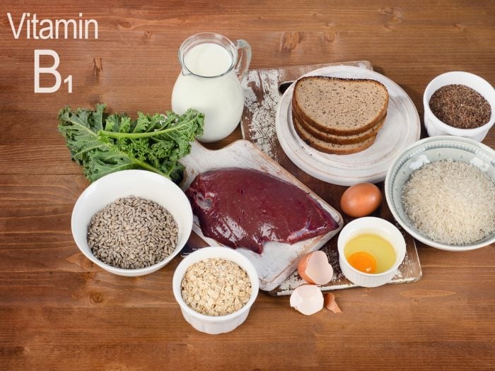 Foods rich in vitamin B1 or thiamin (Milk, bread, beef, eggs, rice, oats, seeds, legumes) on a wooden table