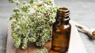 Thyme essential oil bottle and thyme blossoms on a wooden counter