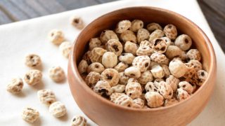 A wooden pot of tiger nuts on a white cloth