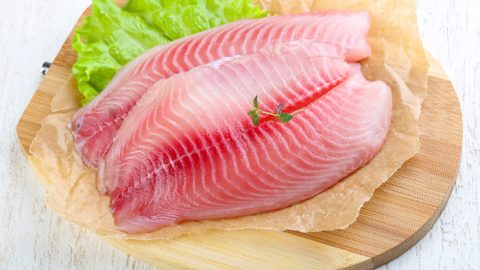 Fish fillet on a wooden plate with lettuce