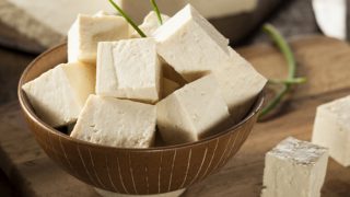A bowl of freshly sliced tofu on a wooden table