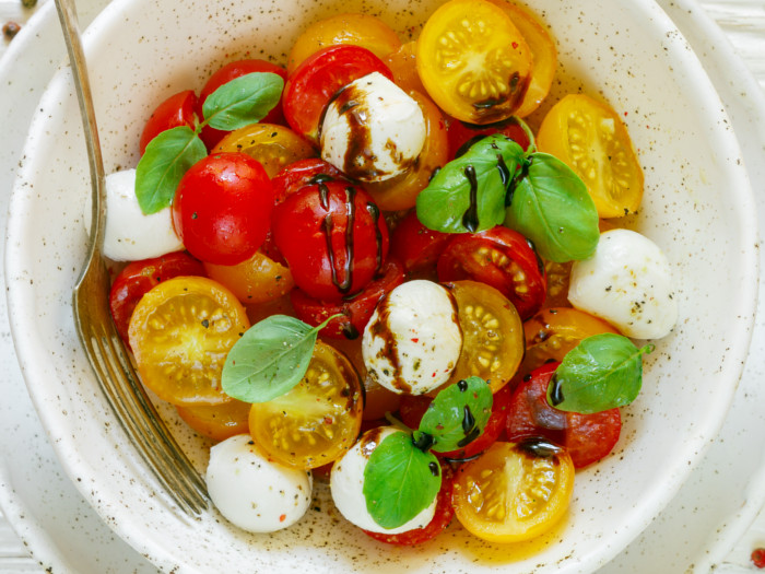 A yellow and red tomato salad in a white bowl with a fork