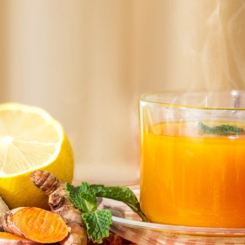 A close up shot of a cup of Turmeric Tea with lemon and ginger