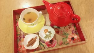 Flatlay picture of a red teapot, two small bowls with spices and a cup and saucer of tea
