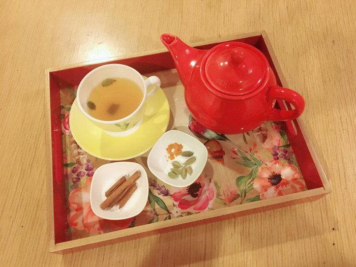 Flatlay picture of a red teapot, two small bowls with spices and a cup and saucer of tea