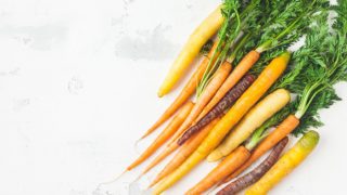 Yellow, red, and orange carrots placed on a white background