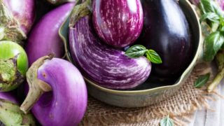 Types of eggplant in a rustic bowl and background