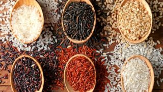 A flat lay picture of different kinds of rice in wooden spoons
