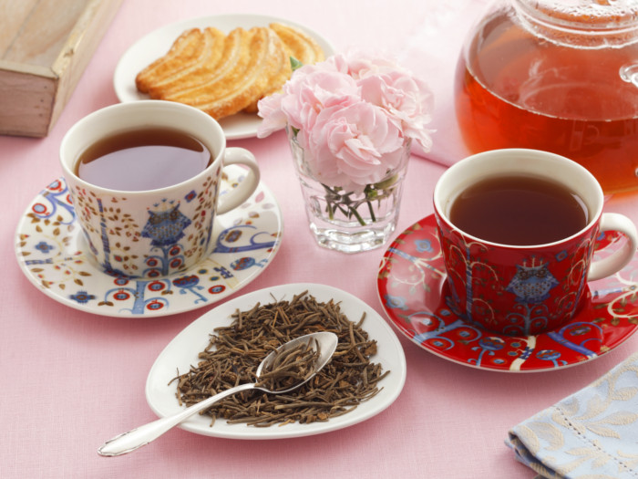 Traditional cups with valerian tea, valerian tea leaves, and a teapot on a table