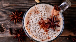 Homemade Chai Tea Latte with anise and cinnamon stick in glass mug on wooden rustic background