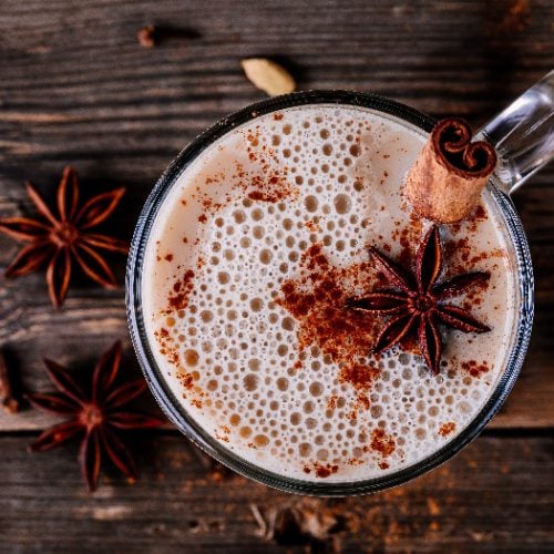 Homemade Chai Tea Latte with anise and cinnamon stick in glass mug on wooden rustic background