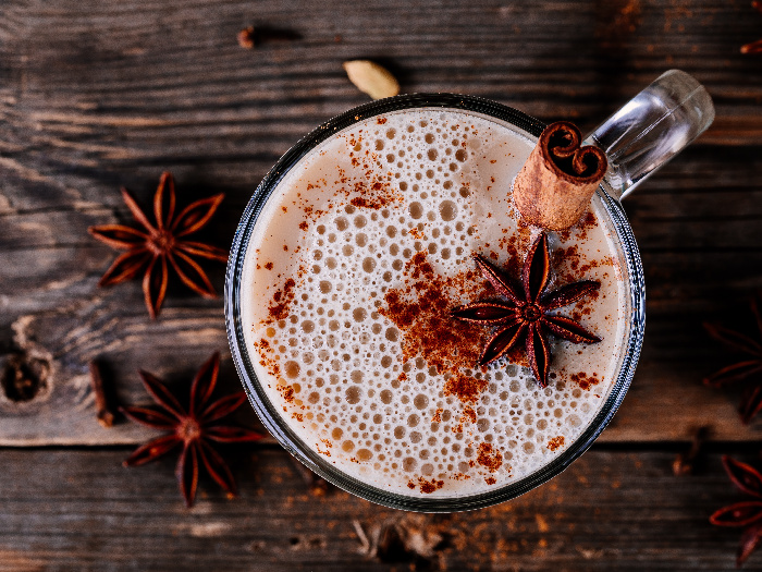 Homemade Chai Tea Latte with anise and cinnamon stick in glass mug on wooden rustic background