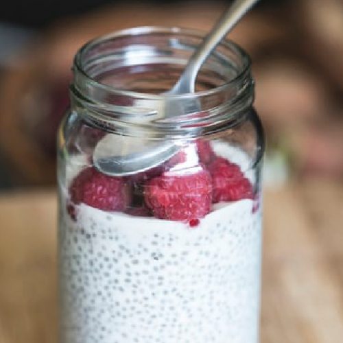 A close-up shot of a glass jar containing vanilla chia pudding garnished with strawberries