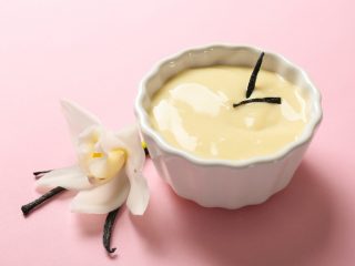 Vanilla Pudding in a white bowl kept atop a pink table, next to a white flower