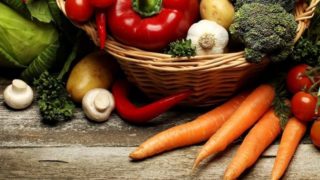 A basket full of vegetables on a wooden surface