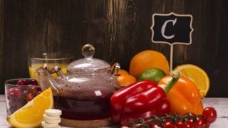 Foods rich in vitamin C (whole and halved sweet limes, red and yellow chili pepper, red cherries) with glasses of sweet lime juice and cherries on a wooden table