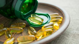 Vitamin D3 supplement yellow capsules on a plate next to an open bottle
