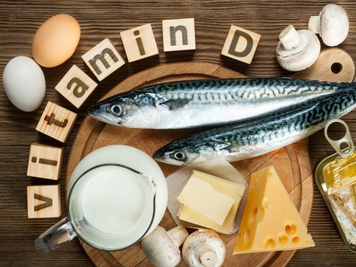 Vitamin D written in blocks with vitamin D-rich foods like eggs, fish, and cheese