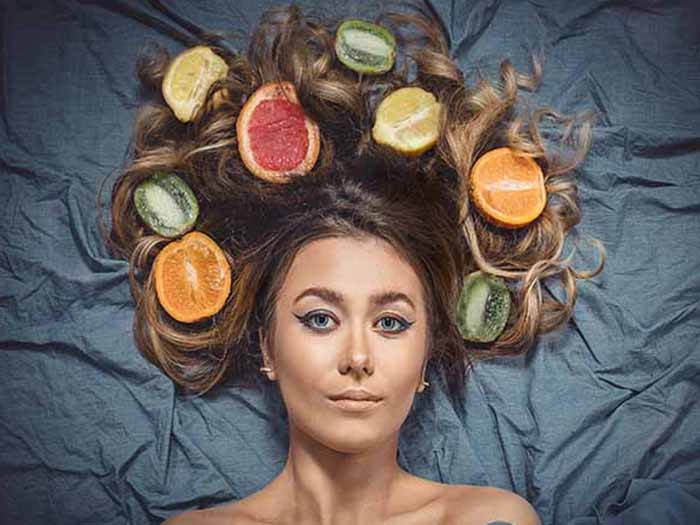 A close-up top angle shot of a woman posing with different citrus fruits.
