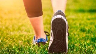 A close-up shot of a woman wearing sports shoes walking on grass