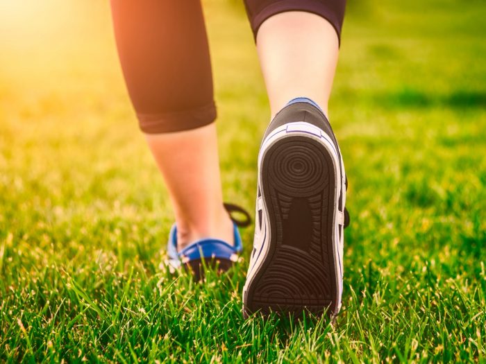 A close-up shot of a woman wearing sports shoes walking on grass