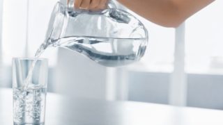 Woman pouring water into a glass from a jug