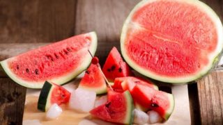 Sliced watermelon and ice cubes on a wooden board