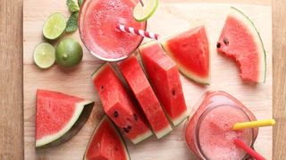 Watermelon juice in a mason jar and a glass with straws, and sliced watermelon