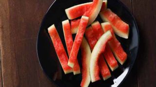 A black plate of watermelon rind cut in pieces on a wooden table