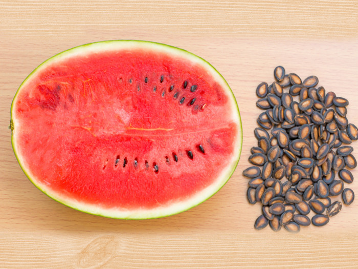 Halved fresh watermelon with watermelon seeds on a wooden table