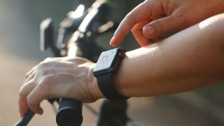 Woman cyclist hands with heart rate icon on a smartwatch