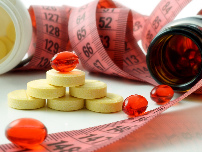 Weight loss supplements next to a measuring tape