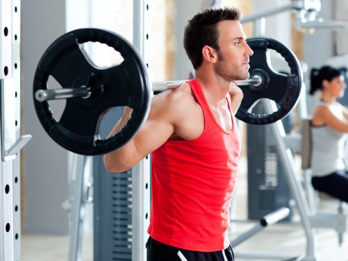 A young man using weight training equipment in the gym