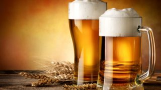 Glasses of wheat beer and wheat ears on a wooden table