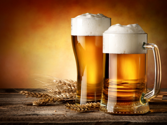 Glasses of wheat beer and wheat ears on a wooden table