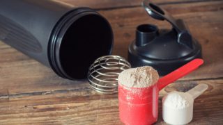A sipping bottle with two spoonfuls of powders placed next to it