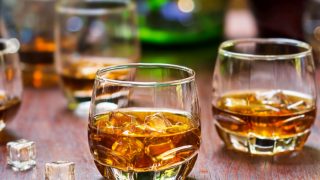 2 glasses of whiskey with ice on a wooden table