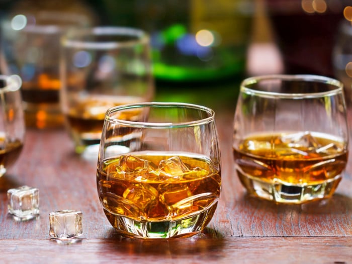 2 glasses of whiskey with ice on a wooden table