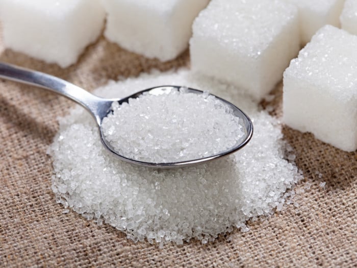 A spoon of sugar with sugar cubes background