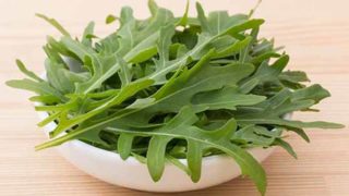 A bowl of fresh green wild lettuce leaves on a wooden table