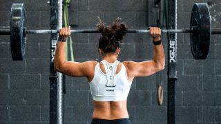 Woman lifting barbell overhead in a gym
