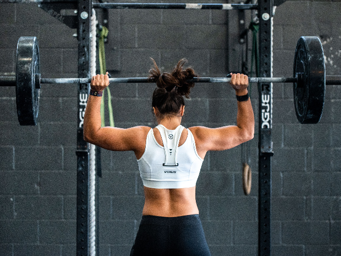 Woman lifting barbell overhead in a gym