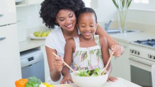 Mother and daughter making a salad together at home in the kitchen
