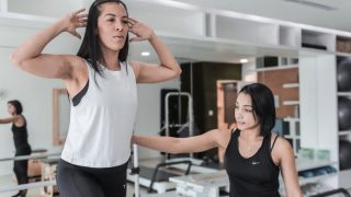 Woman exercising under a trainer's supervision