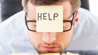 Frustrated young man in formal wear with a sticky note saying help on his forehead