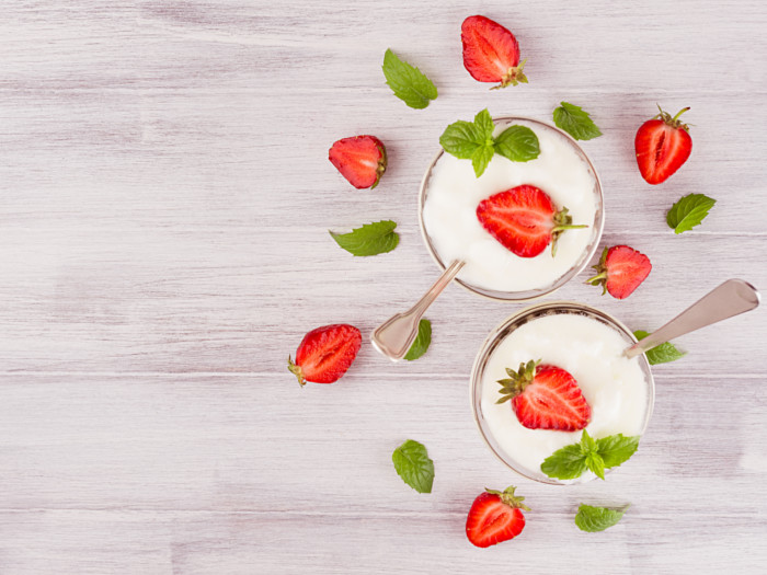 Two cups of yogurt topped with strawberries