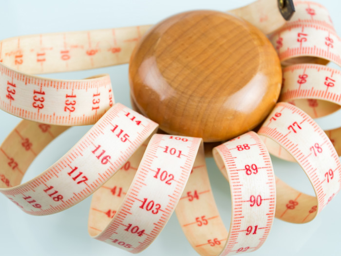 A wooden knob surrounded by a twirling tape measure.