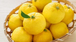A basket of fresh yuzu fruits on a wooden table